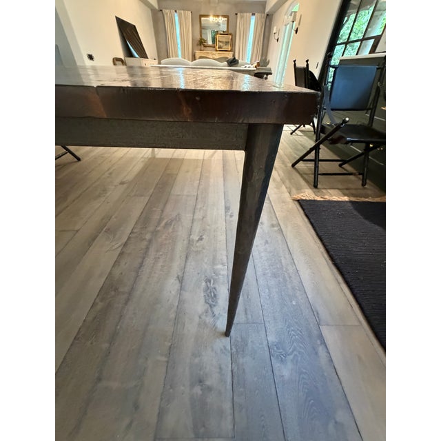 Elegant hand-forged wrought iron tapered legs support a substantial custom-crafted solid wood top, creating a dining table...
