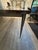 Elegant hand-forged wrought iron tapered legs support a substantial custom-crafted solid wood top, creating a dining table...
