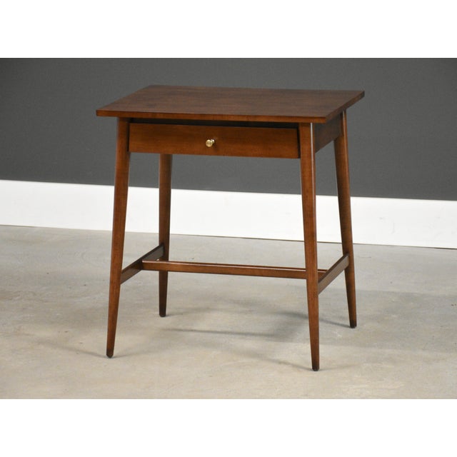 A mid century modern solid maple single drawer nightstand with a polished brass hourglass knob and canted legs designed by...