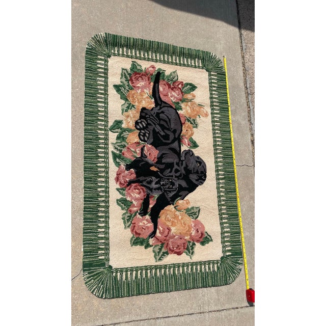 Hand-hooked wool accent rug featuring a black Labrador Retriever and a smaller puppy lying amidst a cluster of pink and...