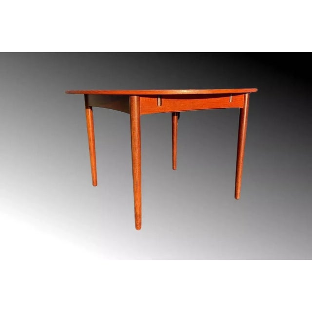 A danish teak circular extending draw leaf dining table, containing two folding leaves, on tapering supports, stamped...