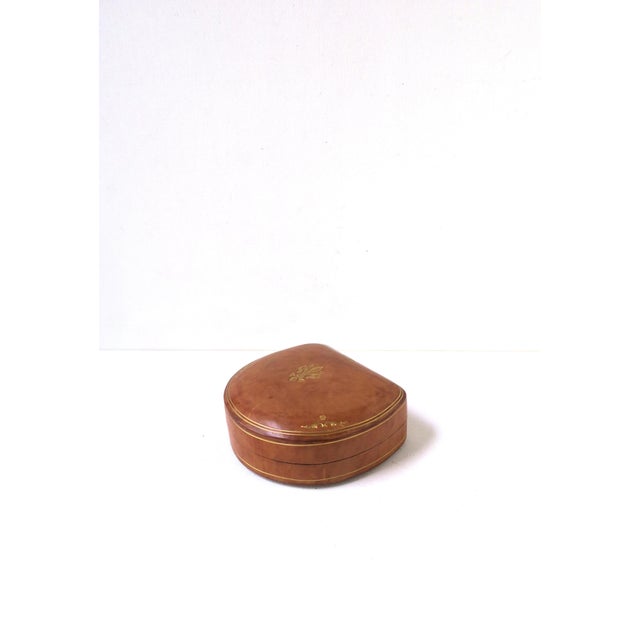 An Italian tan leather jewelry box with gold embossed fleur-de-lis design on top, circa mid-20th century, Italy. Box, with...