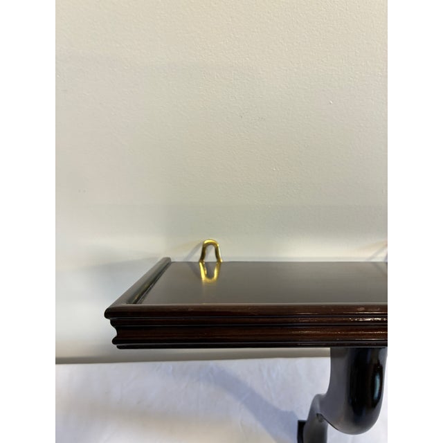 A classic vintage wall shelf by Bombay Company featuring a warm mahogany finish and a graceful curved support bracket....