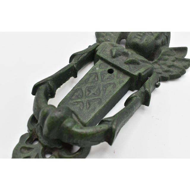 This is an amazing early 20th Century antique cast iron door knocker. It features an angle motif with hinged knocker.