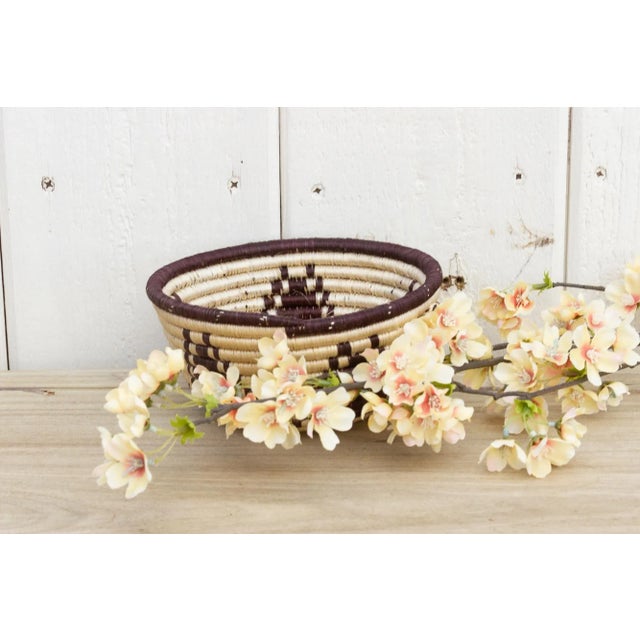 A lovely farmhouse round basket from the Tharu people in Nepal. This vintage basket has a two-tone weaving with a floral...