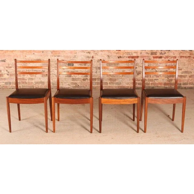 A set of four midcentury g plan dining chairs circa 1960s. Newly upholstered with premium black vinyl. H: 83.5cm w: 49cm...