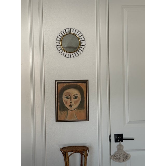 Petite Mid-Century Modern mirror in the style of Josef Frank, featuring a polished brass frame with a rich dark green...