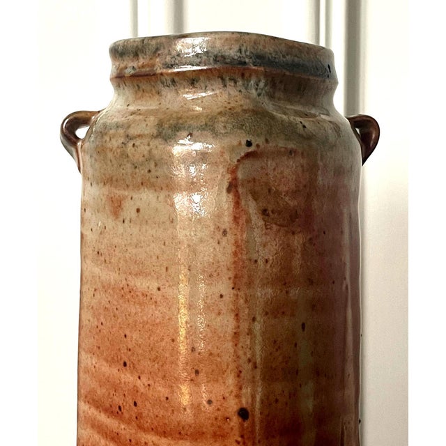 A tall cylinder shape stoneware vase by American studio potter Warren MacKenzie (1924-2018). The vase displays a slightly...