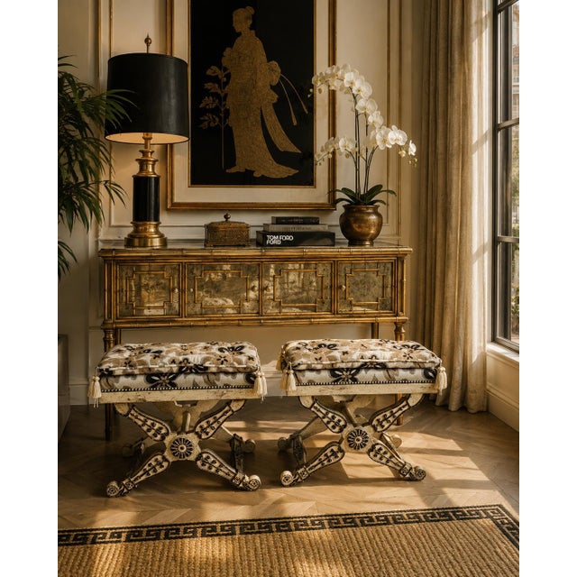 An elegant pair of vintage Maison Jansen-style Neoclassical curule stools featuring intricately carved X-form bases with a...