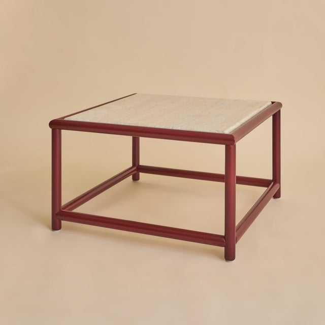 A 1970s Italian coffee table featuring a travertine top set within a lacquered red wood frame. The rectangular stone...