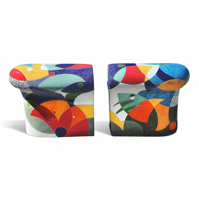 Two ceramic forms that work together as a functional bench, the surface carrying reds, oranges, teals, and greens across...
