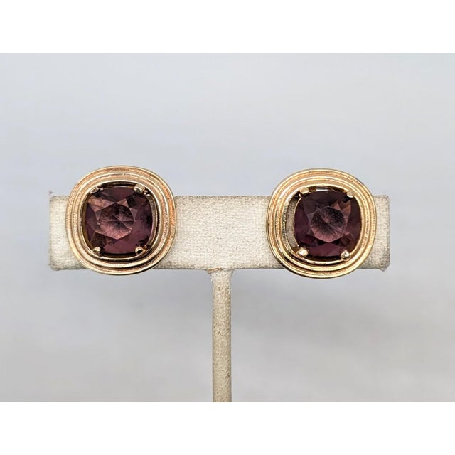1980s goldtone and faux-amethyst clip earrings. Marked "Grosse©" on the clips. Measure: 13/16 inches by 13/16 inches....