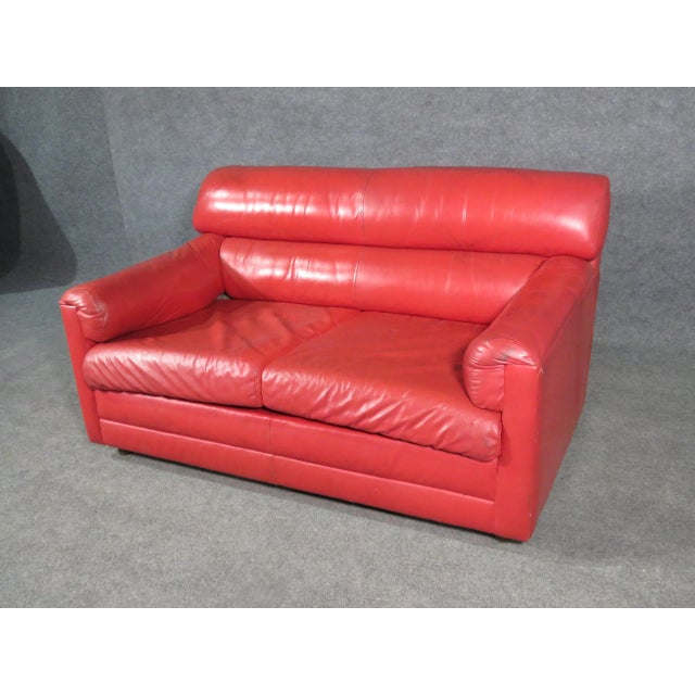 Comfortable and vibrant, this vintage loveseat is upholstered in leather making it durable and easy to clean.