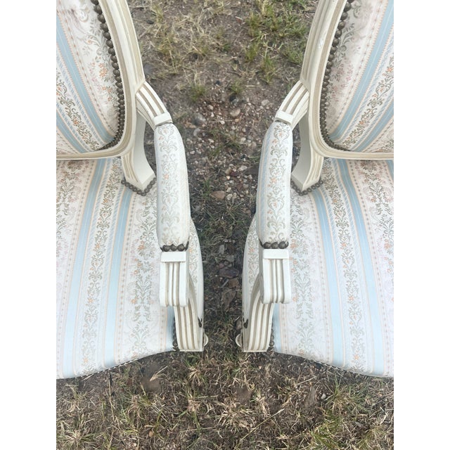 Pair of 19th Century Louis XVI Armchairs featuring hand-carved and painted wood frames with elegant oval backs, fluted...