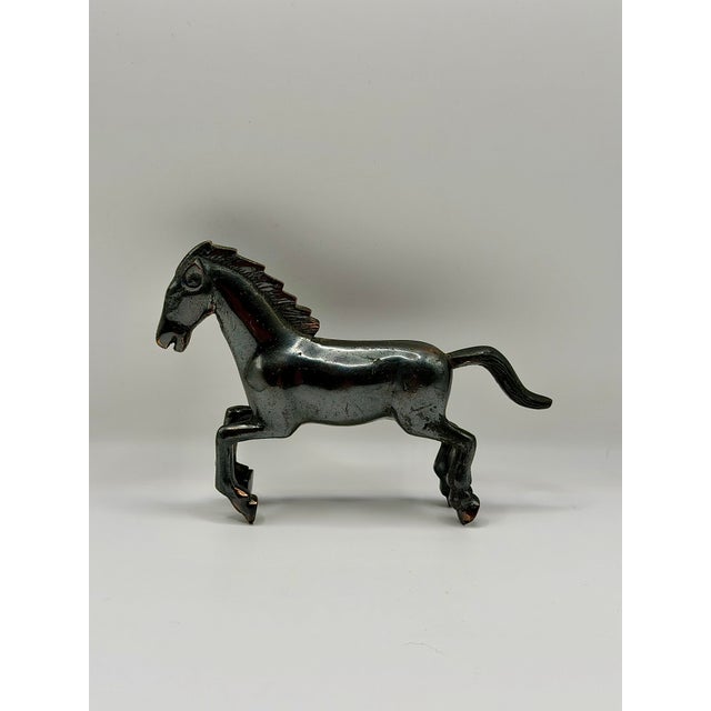 A striking vintage cast metal rearing horse figurine with a dark patinated finish and warm brass-tone wear showing through...