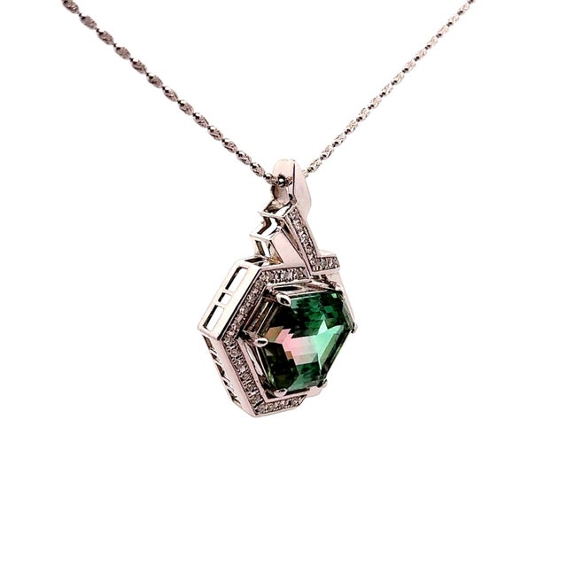 This pendant features a 23.32 carat hexagon-cut tourmaline at its center, displaying a captivating green-pink hue. Crafted...