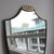 Mid-Century Italian wall mirror with brass frame and beading with hammered cartouche decoration (circa 1950s). The shield-...