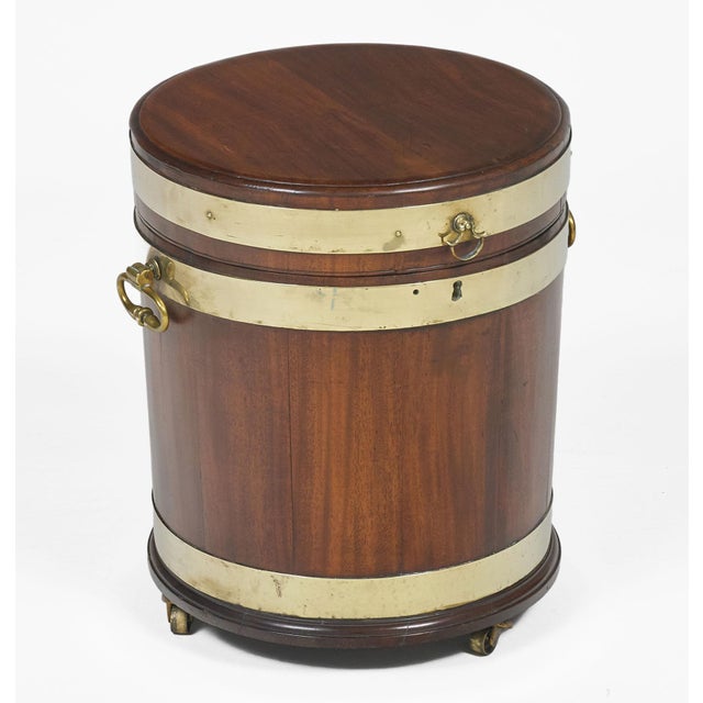 Regency mahogany round brass bound wine cooler with hinged flat lid opening to a zinc lining to protect the wood from...