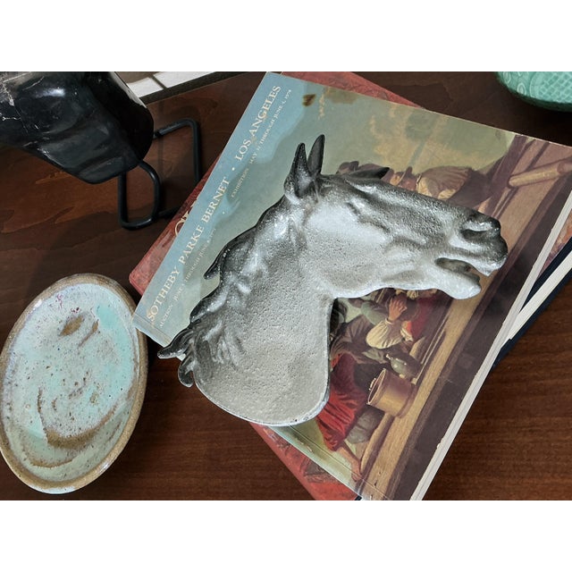 A striking mid-century modern sculptural horse head catchall dish crafted from heavy cast iron and finished with a ceramic...