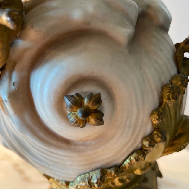 A gorgeous art nouveau porcelaine vase in a shape of a shell standing on a gilt dore bronze base, finished with a dore...