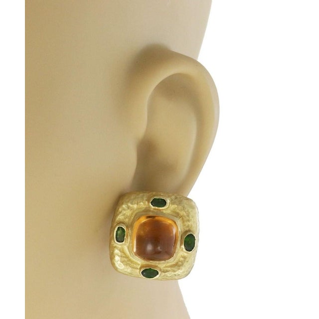 The Kanaris Citrine & Tourmaline 18k Yellow Gold Hammered Square Huggie Earrings are a stunning pair of fine jewelry...