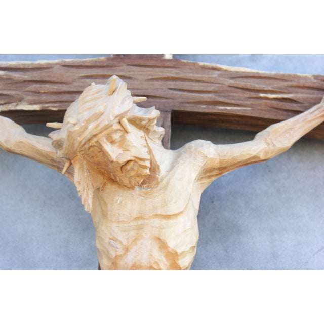 A large and highly detailed hand-carved wooden crucifix, depicting Jesus Christ on the cross, carved with exceptional...