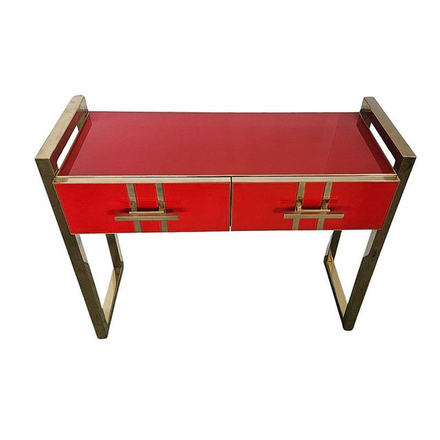 Wooden console, covered in red glass. Enriched by a tubular brass structure. Profiles, handles, legs in brass. Dimensions...