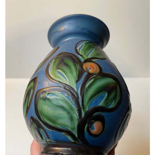 Unusual art deco earthenware vase decorated with flowers in matte cow-horn applied glazes over a blue background. Made at...