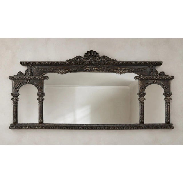 A dramatic vintage architectural wall mirror featuring an ornate dark bronze-tone frame with classical columns, arched...