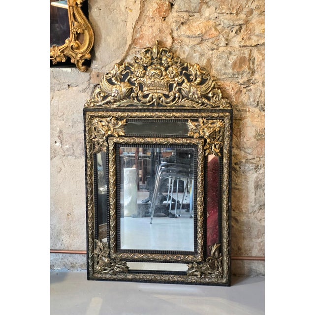 Rectangular mirror with ebonized wood frame, adorned with repoussé and gilded metal plaques decorated with scrolls,...