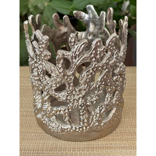 Charming coastal silver-colored jar or pillar candle holder, made by Mariposa. Made of cast aluminum, the inside has a...