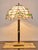 Designer lamp with glass shade in Tiffany style. Lamp body made of polished brass in gold and white. The shade is made of...