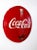 This vintage Coca-Cola advertising sign features a large, three-dimensional metal button design showcasing the iconic red...