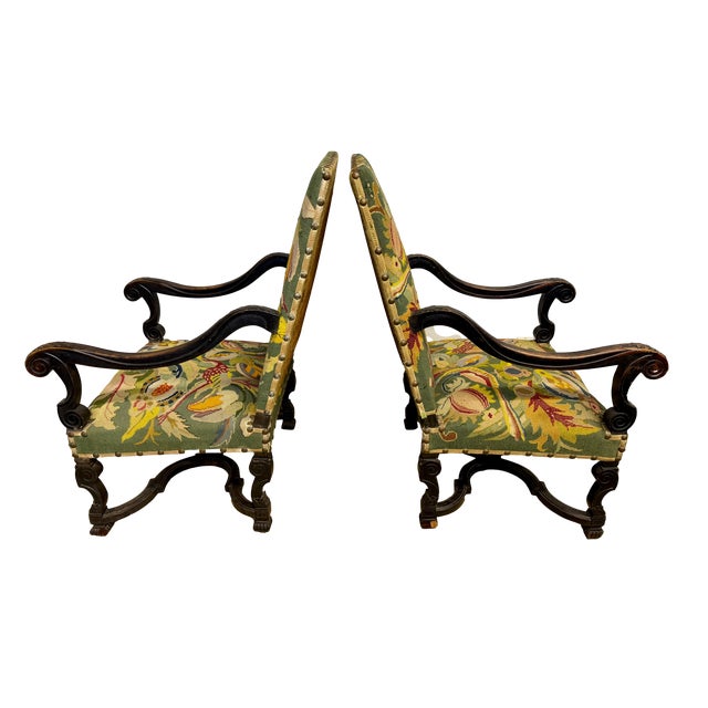 Extraordinary pair of French 18th C baroque ebonized armchairs with the original needlepoint and velvet backs with...