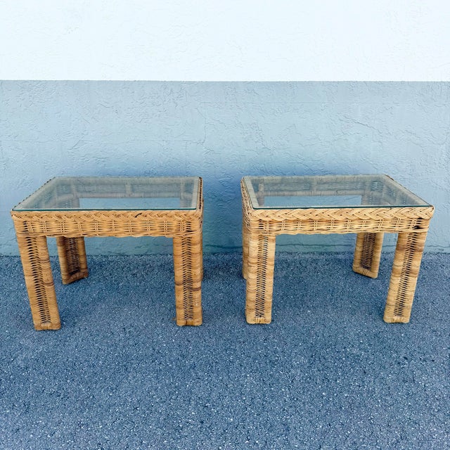 Charming pair of vintage Boho Chic side tables crafted from woven natural rattan and wicker with inset clear glass tops....