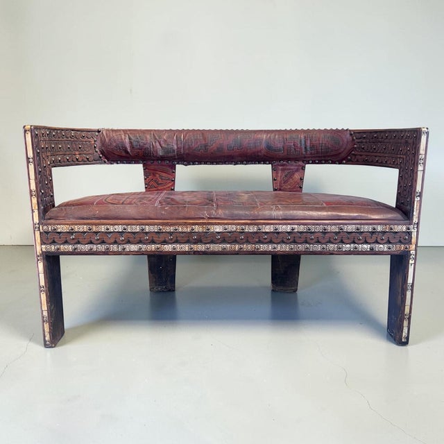 A striking two‑seater settee, likely mid to later 20th century, in the african tribal style. Hardwood, carved and banded...