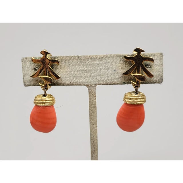 1960s goldtone Asian character tops with faux-coral drops clip earrings. Marked crown "TRIFARI." Measure:1 5/8 inches long...