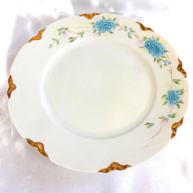 This is a white scalloped plate marked Thomas Bavaria. It has bunches of small blue flowers plus a scalloped gold trimmed...