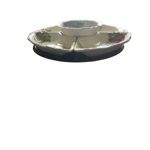 Mid Century California pottery serving set with lazy susan from Maddux. Raised grapes and leaves lay across an off white...