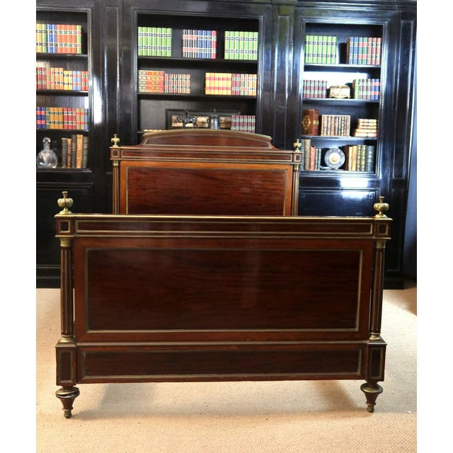 A Louis XVI style bed with brass trim, dating from the 19th century. The fluted posts feature brass trim and beautiful...