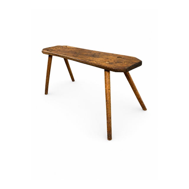 This antique Swedish farm bench handcrafted from solid pine wood, featuring a long plank seat and four simple splayed...