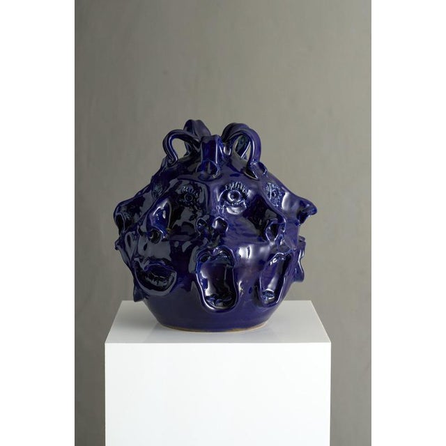 This signed John Rezner cobalt blue ceramic vase with screaming faces is an extraordinary and provocative work of organic...