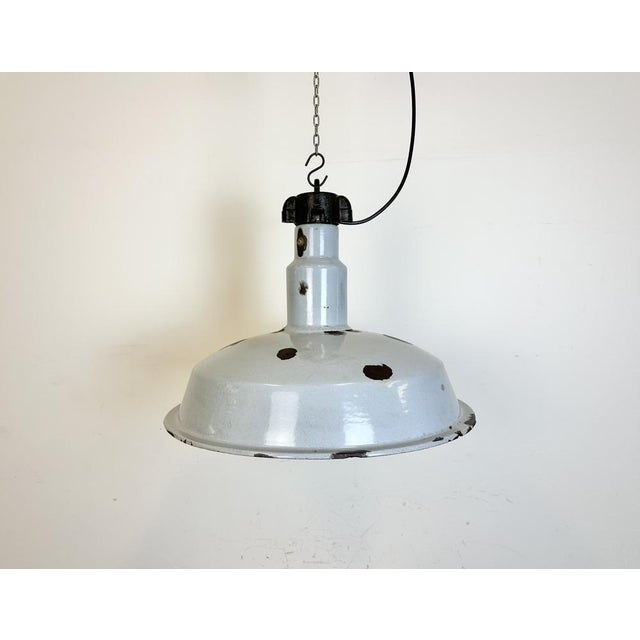 This industrial lamp was made in former Czechoslovakia during the 1950s. It features grey enamel shade with white...