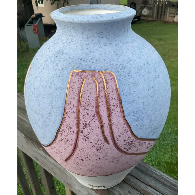 Southwestern pottery vase in light blues, pink and purple mountains outlined in gold. Signed T. Molder