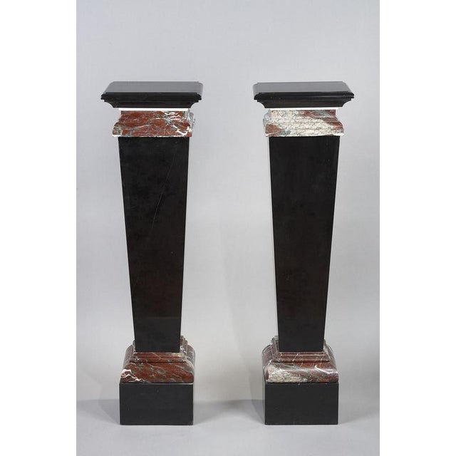 A pair of pilaster sheaths in black and royal red marble with a stack of doucines at the top forming the presentation...
