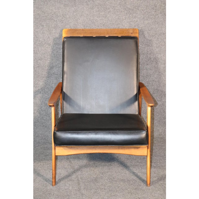 Vintage modern armchair with high back. Two cushions sit on a walnut frame lounge chair with scooping arms.