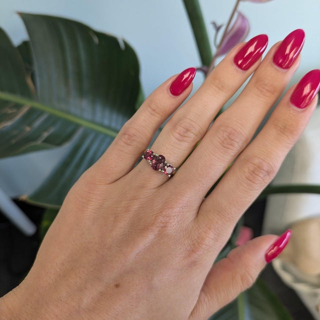 Three natural rubellite tourmalines glow in a vivid pink-red across this solid 14K white gold estate ring, an oval centre...