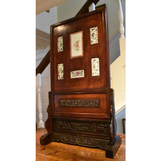 Carved Chinese 19th century screen with polychrome hand painted porcelain tiles set within a dark hardwood frame and...