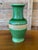 A striking vintage ceramic vase featuring a richly shaded green glaze and a contrasting band of natural fiber wrapping....