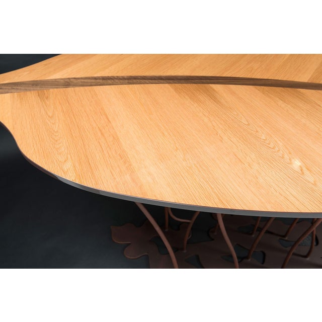 This table has an oak essence and canaletto walnut top and a corten finished steel base.